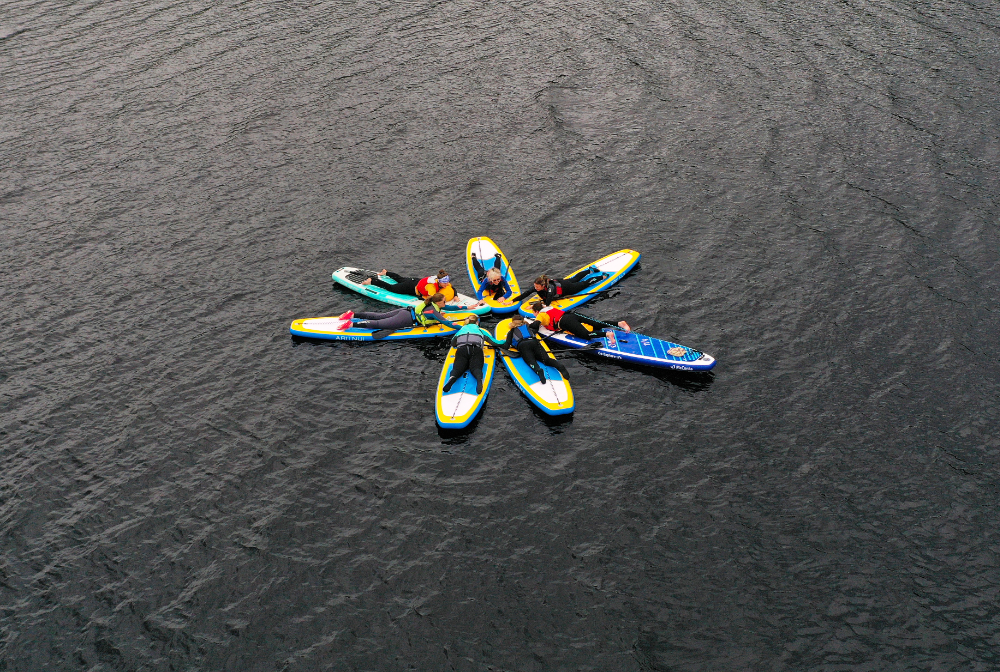 Seven paddle-boarders in a star shape on Loch Migdale, Scotland.